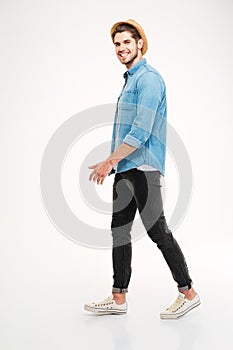 Full length of cheerful young man walking and smiling