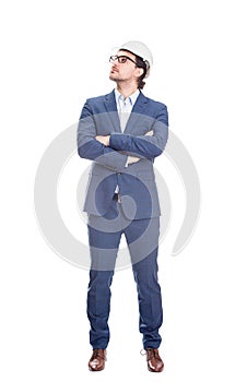 Full length confident engineer, keeps arms crossed wearing protective helmet looks determined aside isolated on white background