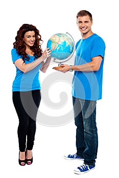 Full length of a couple holding globe over white