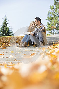 Full length of couple sitting on steps in park