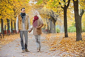 Full length of couple walking while looking up in park during autumn
