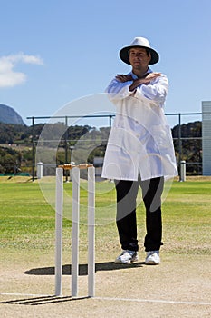 Full length of cricket umpire signaling cancel call sign during match