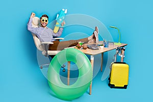 Full length of delighted crazy person sit chair raise fist hold water pistol isolated on blue color background