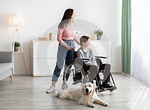 Full length of disabled teen boy with his mother and cute dog spending time together at home