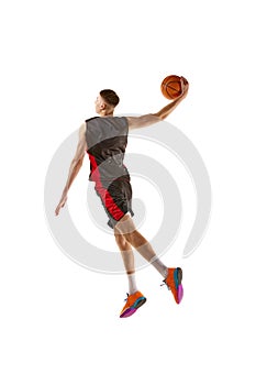 Full-length dynamic image of young man, basketball player practicing, playing isolated over white background. Sport