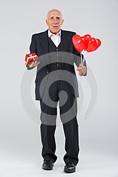 Full-length elderly man on a white background, in the studio, in a black smart suit with balls in his hand and a red