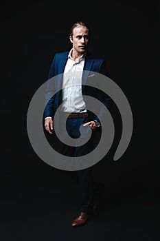 Full length of elegant young handsome man posing in fashionable suit, looking at camera. Studio shot