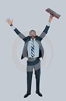 Full length of an excited handsome business man with arms raised in success - Isolated on white.