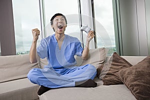 Full length of excited mid adult man playing video game in living room