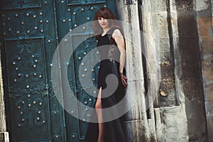 Full-length fashion model in black dress posing in the street ne