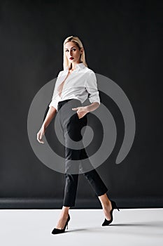 Full length fashion portrait of young stylish woman posing on black background.