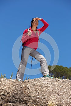 Full length female hiker standing over the cliff and looking away