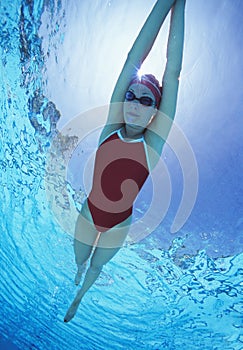 Full length of female swimmer in United States with arms raised swimsuit swimming in pool