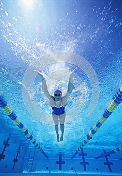 Full length of female swimmer in United States swimsuit swimming in pool