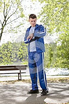 Full length of fit man checking time on path in park