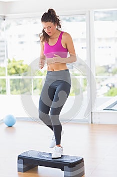 Full length of a fit woman performing step aerobics exercise