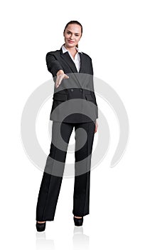 Full length front view of smiling attractive business woman in black formal suit holds out her hand for a handshake. Isolated on