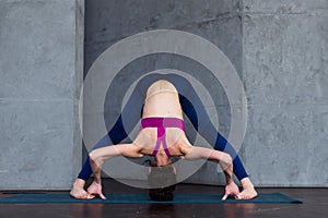 Full-length front view of sporty young woman practicing yoga doing standing straddle forward bend pose, Prasarita photo