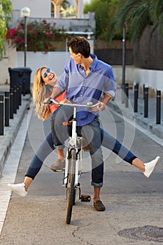 Full length fun couple riding bicycle together on path