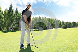 Full length of golf player playing golf on sunny day. Professional male golfer taking shot on golf course