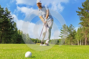 Full length of golf player playing golf on sunny day. Professional male golfer taking shot on golf course.