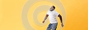 Full length of handsome young black man jumping against yellow background.