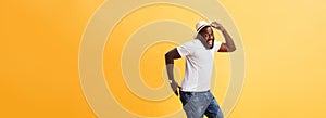 Full length of handsome young black man jumping against yellow background.