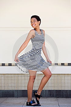 Full length happy young black woman in striped dress