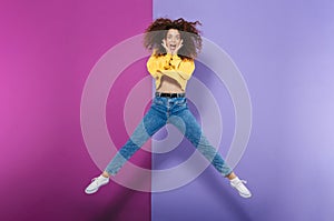 Full length image of amazed happy curly woman swearing casual clothes smiling and jumping