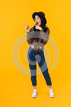 Full length image of asian woman smiling and pointing fingers at copyspace