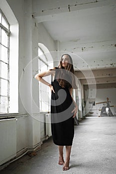 Full length image of a beautiful young woman in black dress, looking at the side.