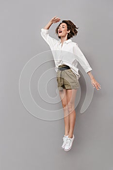 Full length image of caucasian woman 20s smiling and jumping, is