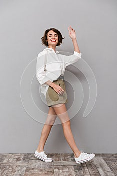 Full length image of gorgeous woman 20s smiling while walking, i
