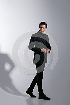 Portrait of handsome young man in black stylish suit, isolated on white background. Full length image.