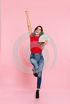 Full-length image of happy brunette woman rejoice and holding money