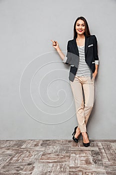 Full length image of Happy business woman pointing on copyspace