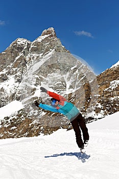 Full length image of a jumping skier in equipment, in the sunny day, on the high mountain background