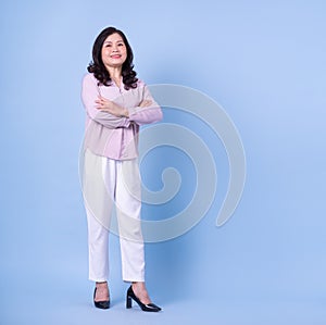 Full length image of middle aged Asian woman on blue background