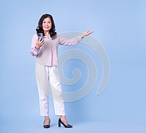 Full length image of middle aged Asian woman on blue background