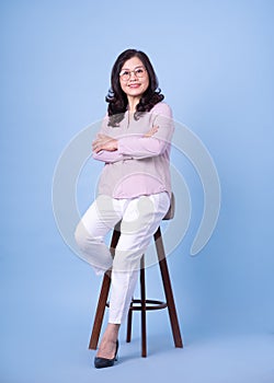 Full length image of middle aged Asian woman on blue background