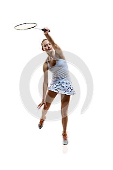 Full-length image of motivated athlete in motion, young girl, badminton player hitting shuttlecock in jump isolated over