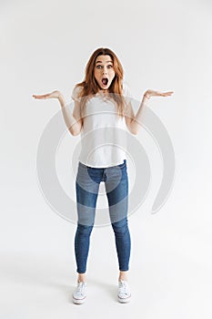 Full length image of Shocked woman in t-shirt shrugs shoulders