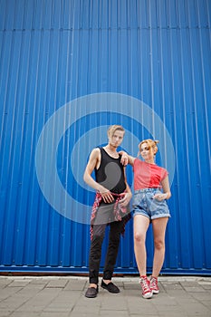 Young modern stylish hipsters couple on blue background, sunny portrait couple teenagers.