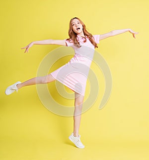 Full length image of young Asian girl standing on yellow background