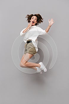 Full length image of young girl 20s smiling and jumping, isolate