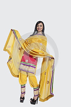 Full length of an Indian woman in salwar kameez standing over gray background photo