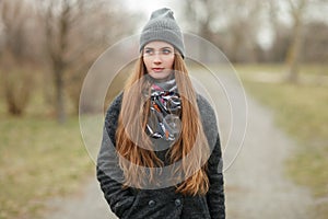 Full length lifestyle portrait of young and pretty adult woman with gorgeous long hair posing in city park with shallow depth of f