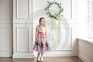 Full-length of little smiling girl child in colorful dress posing indoor