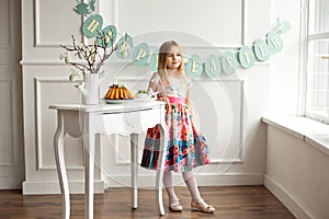 Full length of a little smiling girl in colorful dress posing in a decorated room for the holiday Easter is waiting for