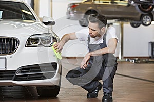 Full length of maintenance engineer cleaning car in workshop